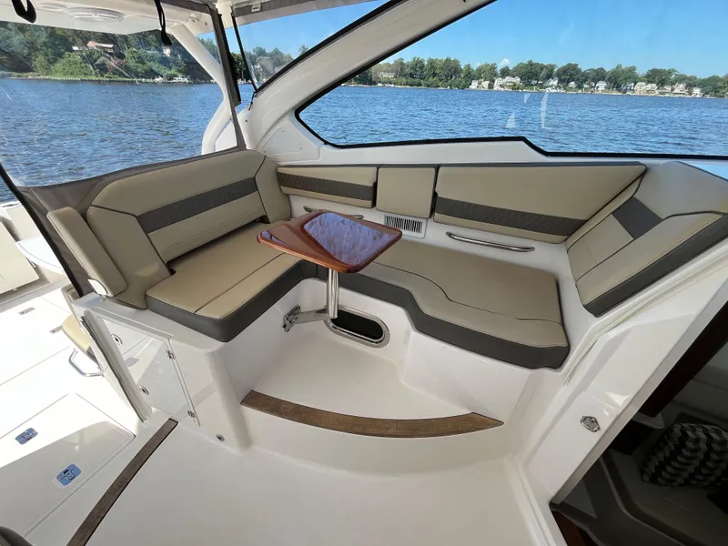 Slide: The Image of 2018 Pursuit DC 365 Dual Console boat interior with cushioned seating and small table. - 20