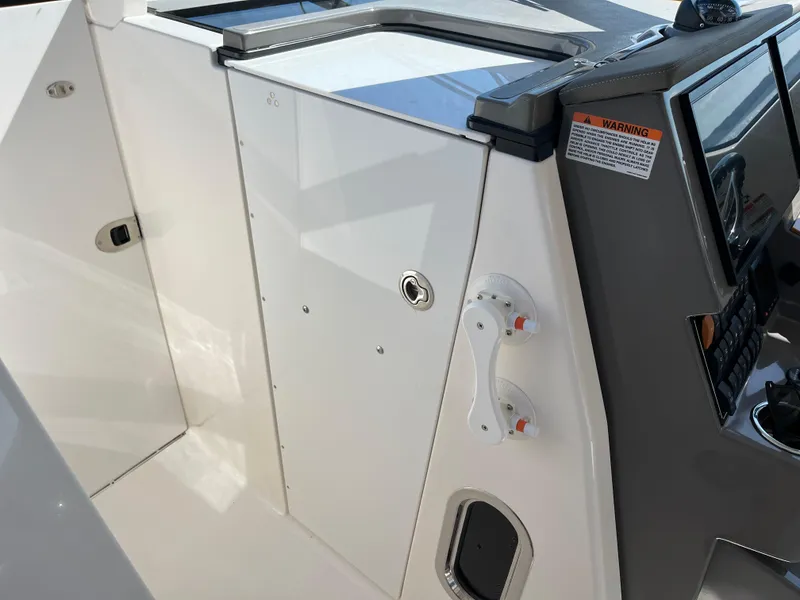 Slide: The Image of 2018 Pursuit DC 365 Dual Console boat interior, featuring control panel and storage compartment. - 36