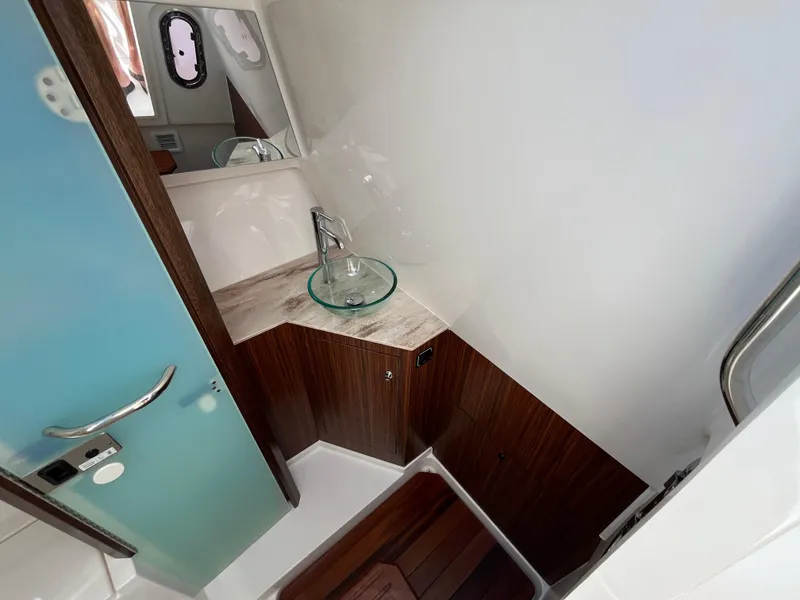 Slide: The Image of 2018 Pursuit DC 365 Dual Console boat interior with modern sink and wood accents. - 38
