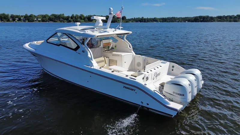 Slide: The Image of 2018 Pursuit DC 365 Dual Console boat cruising on a lake with clear skies. - 4