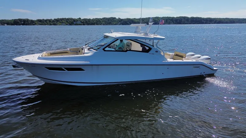 Slide: The Image of 2018 Pursuit DC 365 Dual Console boat on a serene lake. - 5