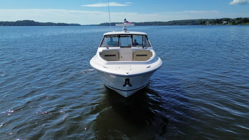 Slide: The Image of 2018 Pursuit DC 365 Dual Console boat on calm water, front view. - 6