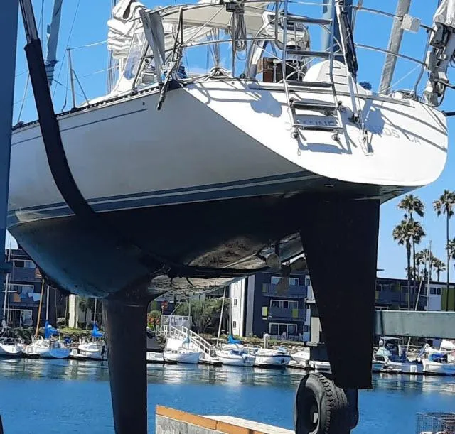 Slide: The Image of 1987 C&C 38 MKIII sailboat in dry dock, marina background, clear blue sky. - 26