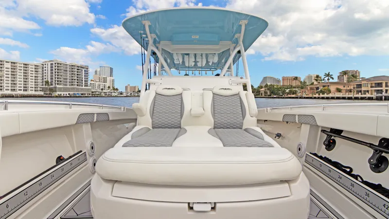 Slide: The Image of 2021 Invincible 42 Center Console Cabin boat with luxurious seating and city skyline backdrop. - 15