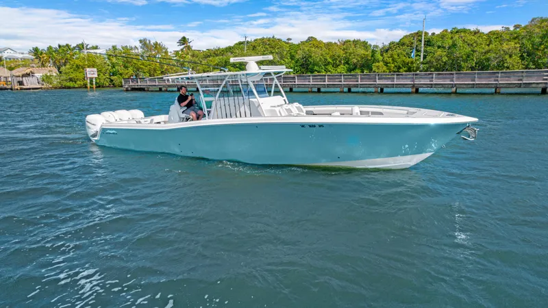 Slide: The Image of 2021 Invincible 42 Center Console Cabin boat on water, sunny day, lush greenery background. - 2