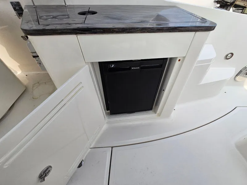 Slide: The Image of 2014 Sea Ray 350 Sundancer boat kitchenette with mini fridge and open cabinet. - 11