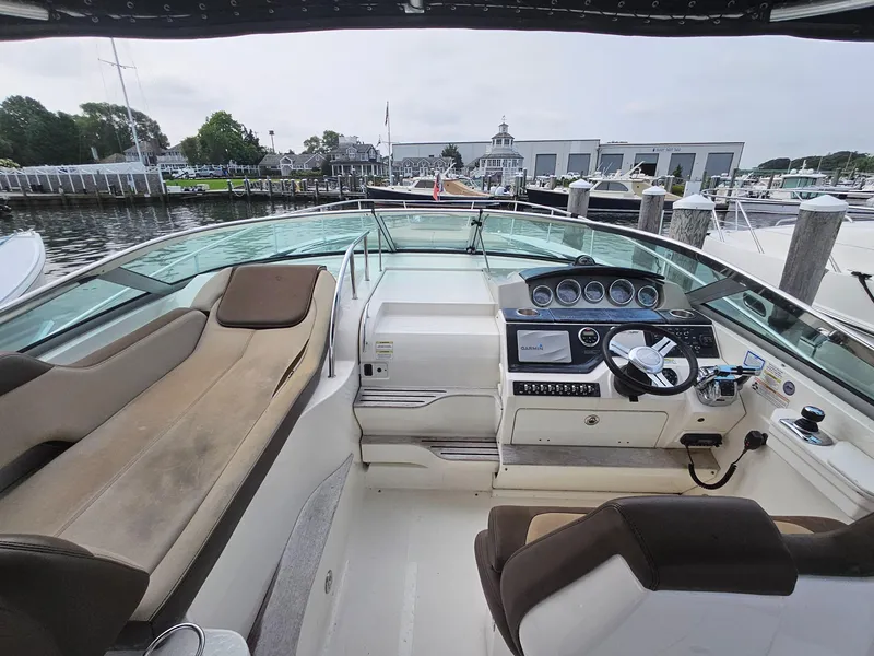 Slide: The Image of 2014 Sea Ray 350 Sundancer cockpit with helm, seating, and marina view. - 4