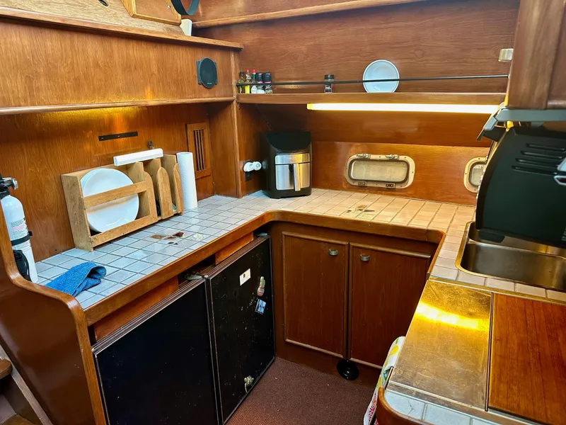 Slide: The Image of Cozy kitchen area in a 1986 Cytra Bavaria 40 yacht with wooden cabinetry and tiled countertops. - 13
