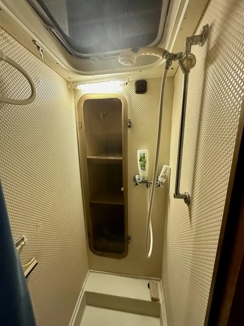 Slide: The Image of Compact shower area in 1986 Cytra Bavaria 40 yacht, featuring a skylight and storage shelves. - 19