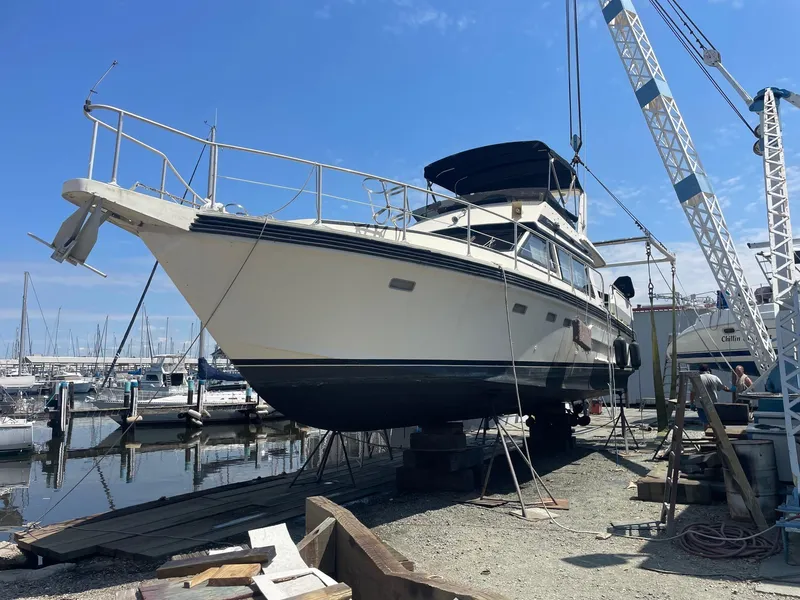 Slide: The Image of 1986 Cytra Bavaria 40 yacht on dry dock with cranes, marina background. - 23