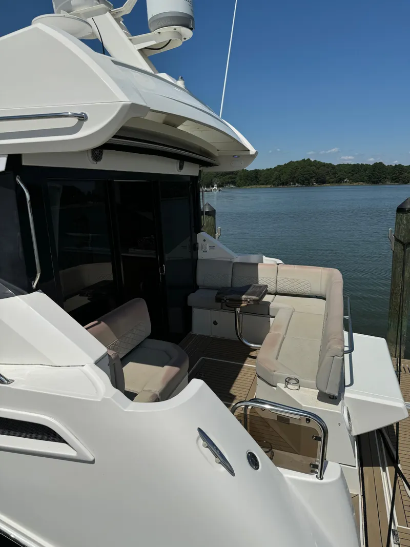 Slide: The Image of 2017 Sea Ray Sundancer 460 yacht with spacious deck and seating, docked by a serene lake. - 11