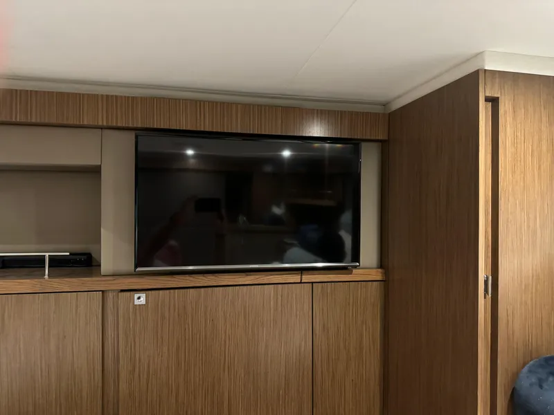 Slide: The Image of Interior of 2017 Sea Ray Sundancer 460 with mounted TV and wooden cabinetry. - 28