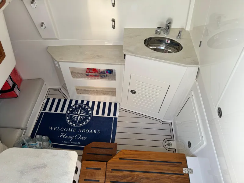 Slide: The Image of 2024 Sailfish 360 CC boat interior with sink, storage, and welcome mat. - 24