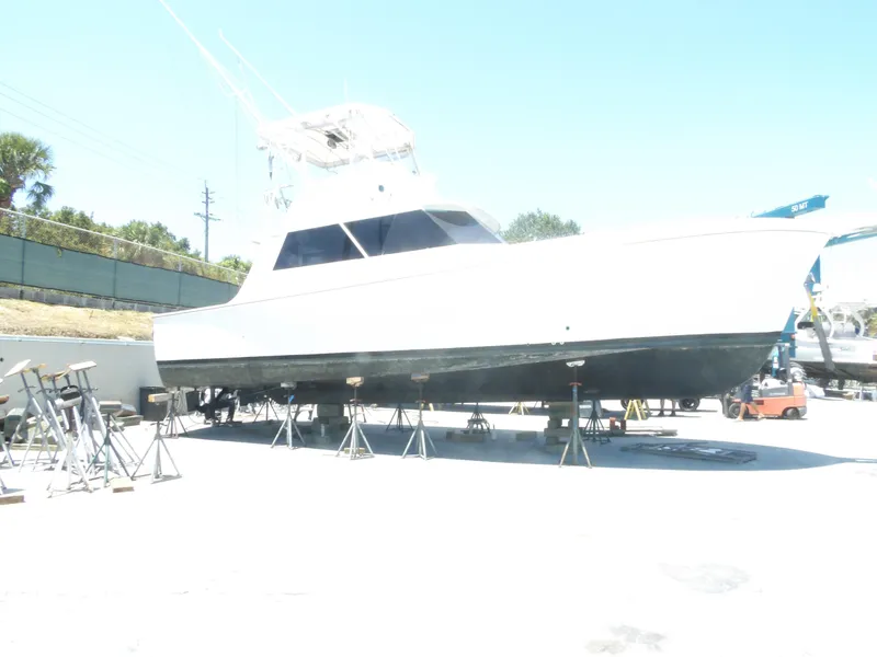 Slide: The Image of 1967 Hatteras Convertible yacht on dry dock, elevated on stands, under clear blue sky. - 10