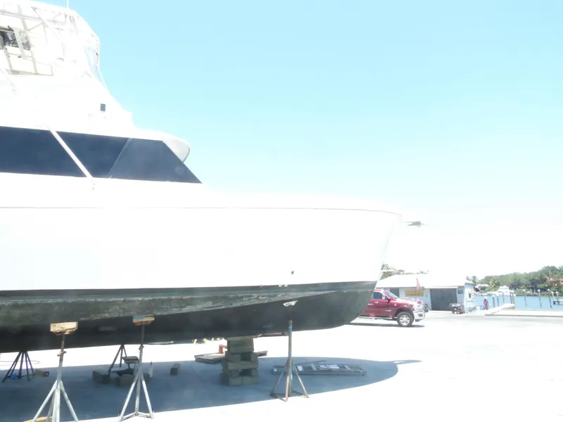 Slide: The Image of 1967 Hatteras Convertible yacht on dry dock, supported by stands, under clear blue sky. - 22