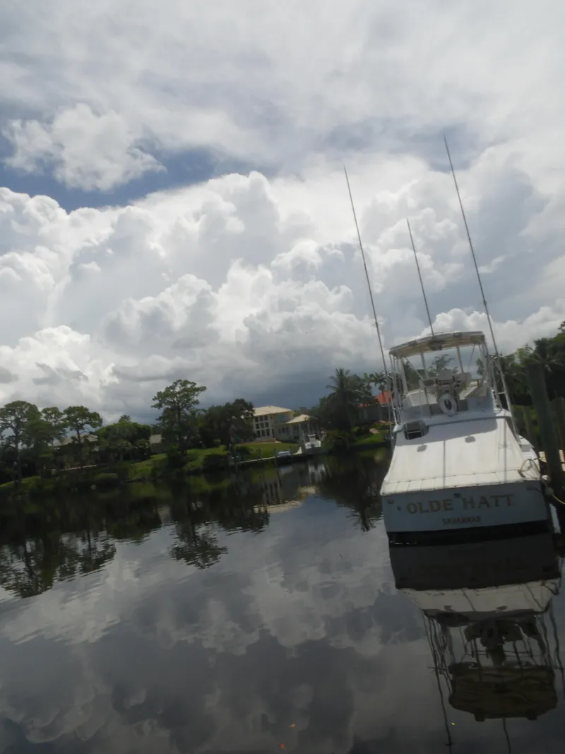 Slide: The Image of 1967 Hatteras Convertible boat docked on a calm lake under cloudy skies. - 3