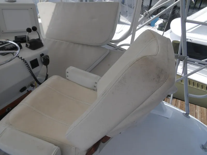 Slide: The Image of Captain's chair on 1967 Hatteras Convertible boat, featuring white upholstery and control panel. - 35