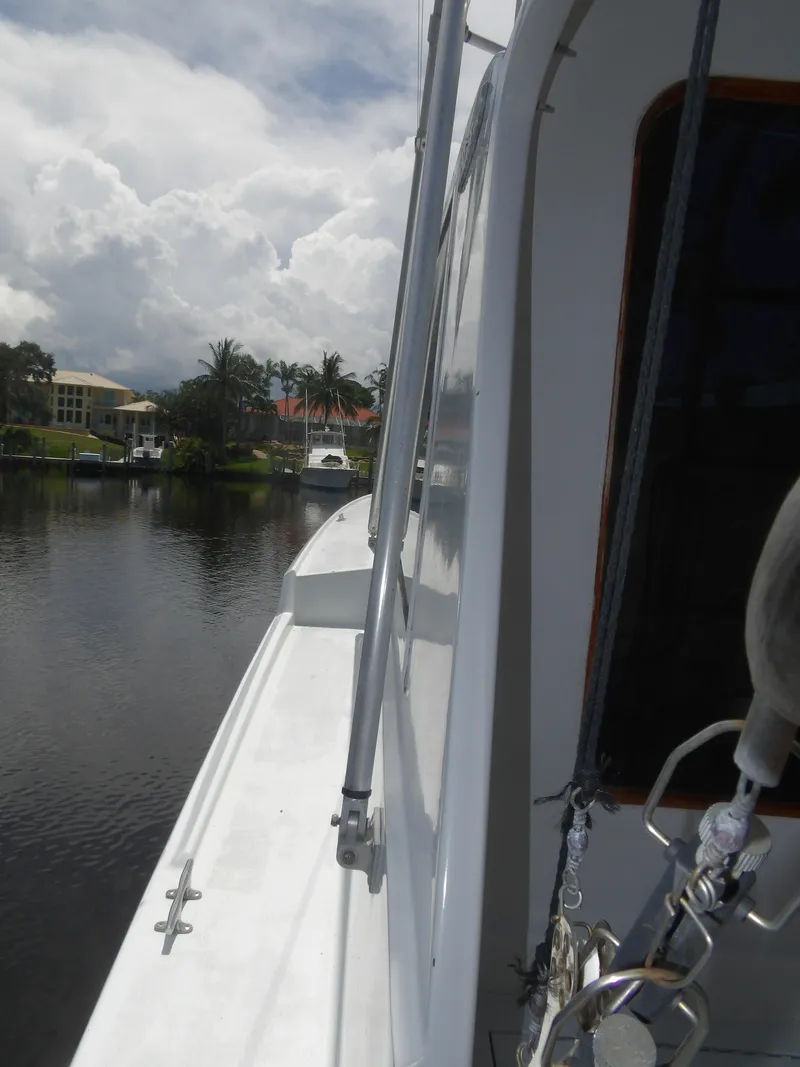 Slide: The Image of 1967 Hatteras Convertible yacht docked by a serene waterfront with palm trees. - 6