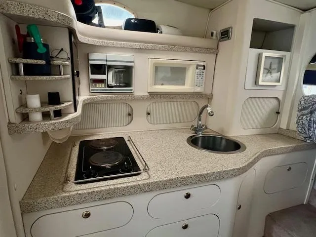 Slide: The Image of Compact kitchen in a 2000 Rinker Fiesta Vee 342 boat with stove, sink, and microwave. - 12