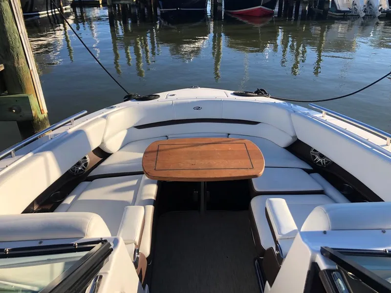 Slide: The Image of 2017 Regal 2800 boat interior with white seating and wooden table, docked by the water. - 37