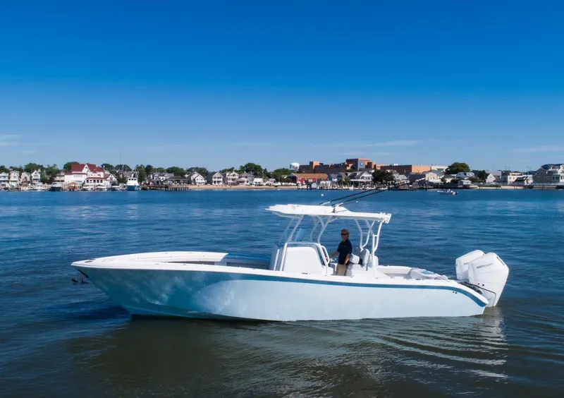 The Image of 2025 Yellowfin 32 Offshore boat cruising on calm waters near a coastal town. - 1