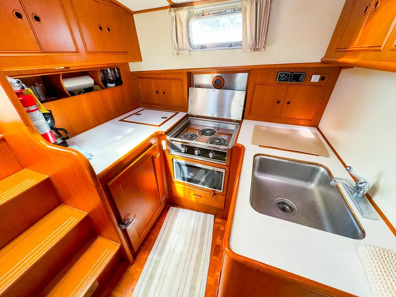 Slide: The Image of 1995 Grand Banks 38 Eastbay EX yacht kitchen with wood cabinetry, stove, and sink. - 23