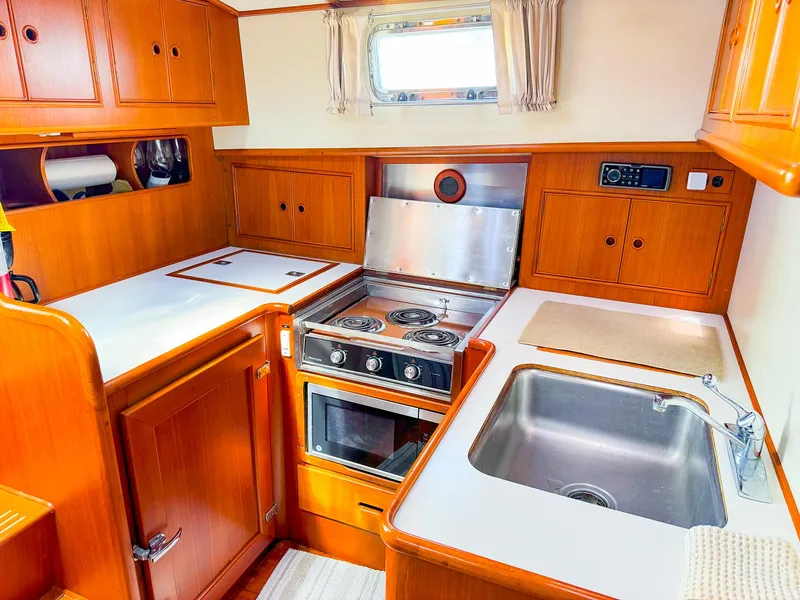 Slide: The Image of 1995 Grand Banks 38 Eastbay EX yacht kitchen with stove, sink, and wooden cabinetry. - 24