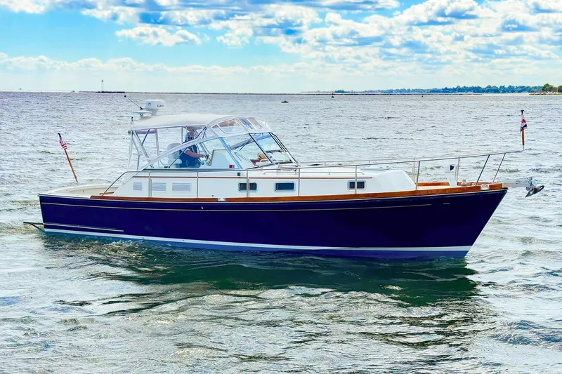 Slide: The Image of 1995 Grand Banks 38 Eastbay EX cruising on open water under a partly cloudy sky. - 36