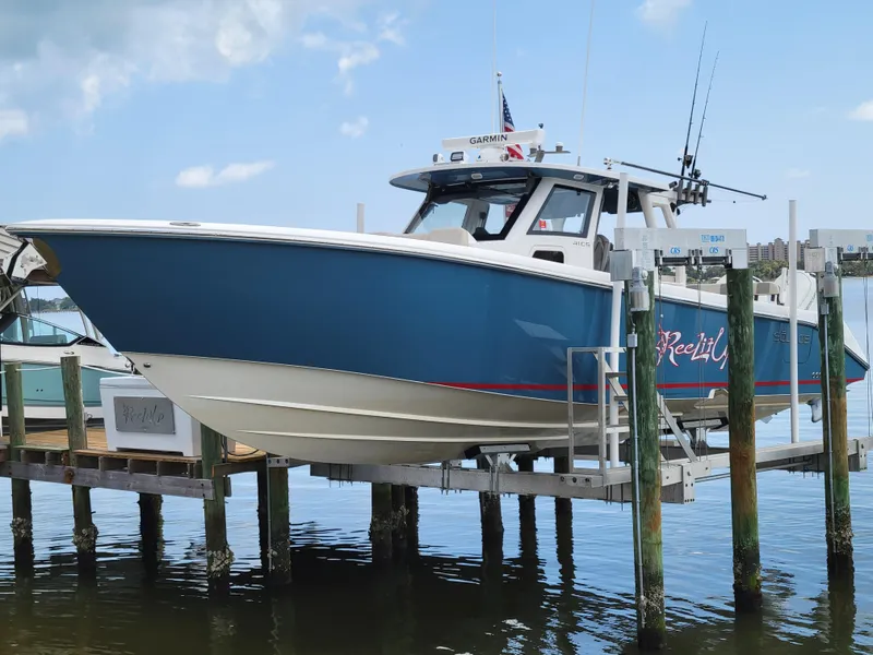 The Image of 2023 Solace 41 CS boat docked, blue hull, fishing rods, clear sky. - 0