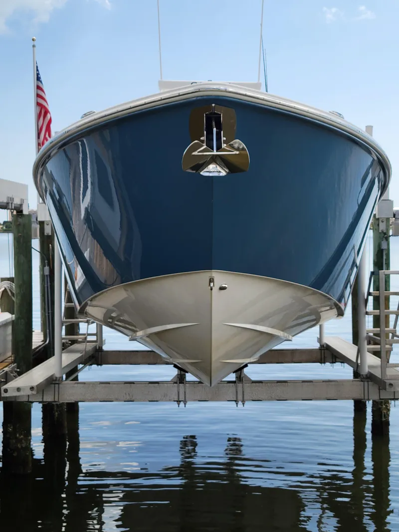 Slide: The Image of 2023 Solace 41 CS boat on lift with American flag in background. - 2