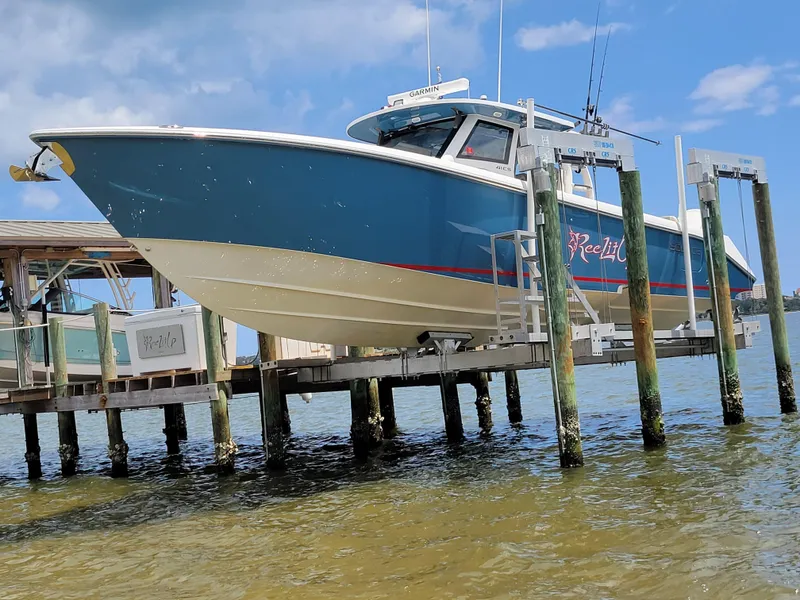 Slide: The Image of 2023 Solace 41 CS boat docked on lift, blue hull, sunny day. - 4
