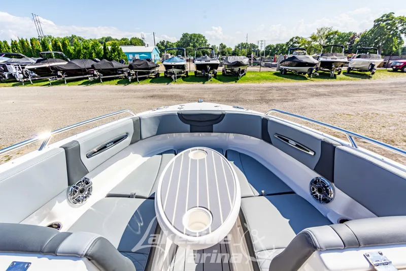 Slide: The Image of 2025 Chaparral 247 SSX boat interior with seating and table, parked in a marina. - 33