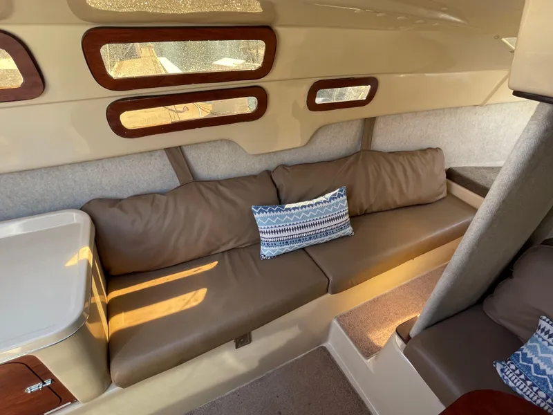 Slide: The Image of Interior of 2006 MacGregor 26M sailboat with brown seating and decorative pillow. - 14