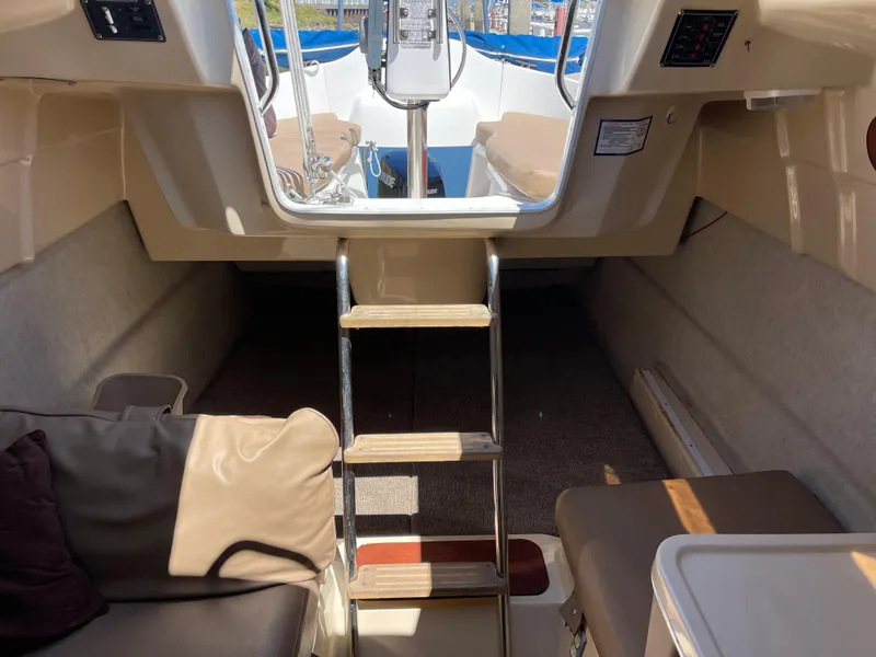 Slide: The Image of Interior view of a 2006 MacGregor 26M sailboat, featuring a cozy cabin and ladder. - 21