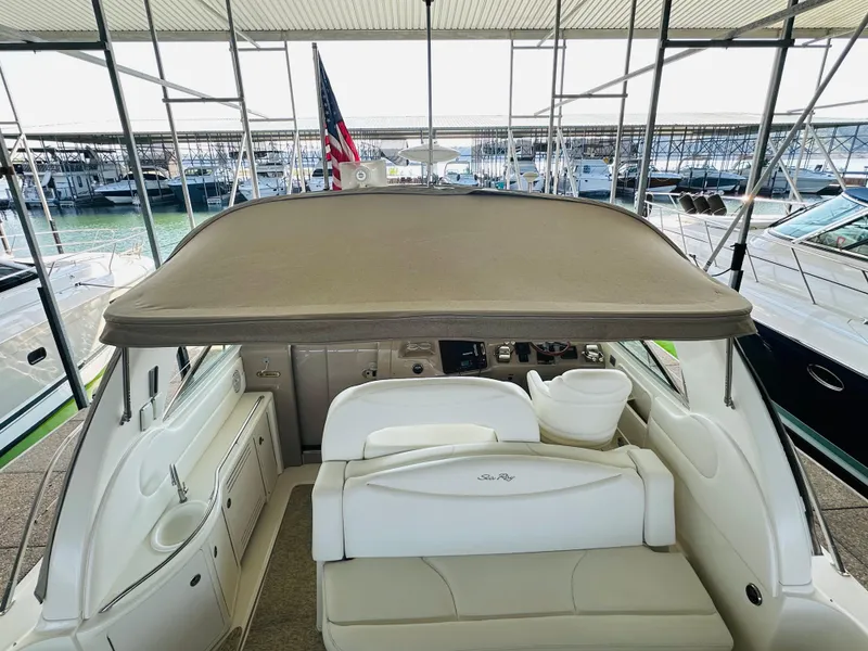 Slide: The Image of 2002 Sea Ray 410 Express Cruiser interior with seating and helm, docked in marina. - 23