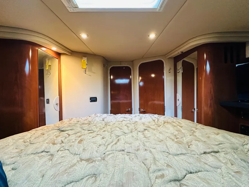 Slide: The Image of Interior cabin of 2002 Sea Ray 410 Express Cruiser with cozy bedding and wooden finishes. - 35