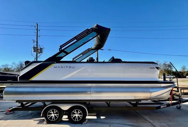 Slide: The Image of 2023 Manitou EXPLORE 22 pontoon boat on trailer under clear blue sky. - 1