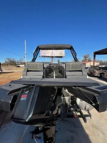 Slide: The Image of 2023 Manitou EXPLORE 22 boat with powerful outboard motor, parked outdoors under clear blue sky. - 11