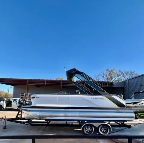 Slide: The Image of 2023 Manitou EXPLORE 22 pontoon boat on trailer under clear blue sky. - 2