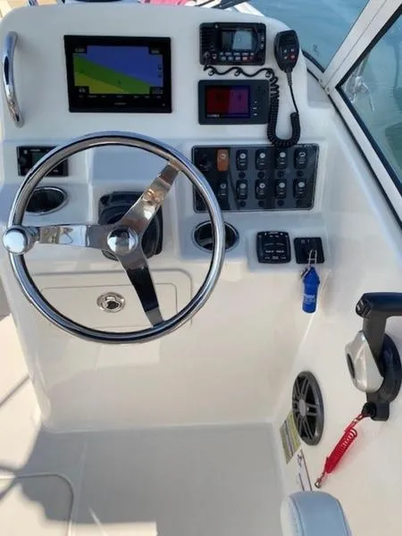 Slide: The Image of 2022 Grady-White Freedom 215 boat dashboard with steering wheel and navigation controls. - 11