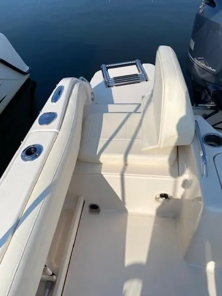 Slide: The Image of 2022 Grady-White Freedom 215 boat interior with seating and motor, docked on calm water. - 15