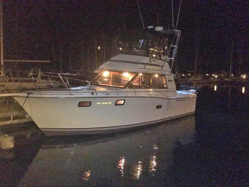 Slide: The Image of 1988 Carver 3227 yacht docked at night, illuminated by onboard lights. - 3