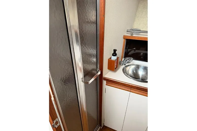 Slide: The Image of 1988 Carver 3227 Convertible bathroom with shower, sink, and wooden cabinetry. - 13
