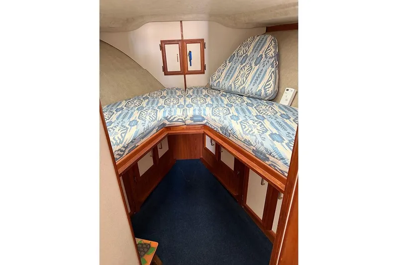 Slide: The Image of 1988 Carver 3227 Convertible cabin with patterned bedding and wooden storage cabinets. - 16