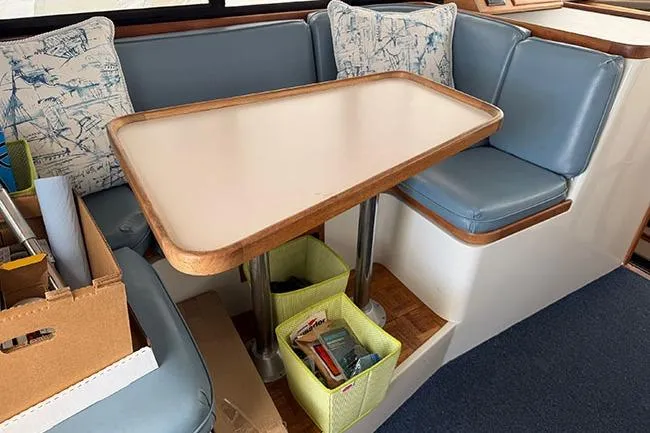 Slide: The Image of 1988 Carver 3227 Convertible interior with blue seating, table, and storage baskets. - 18