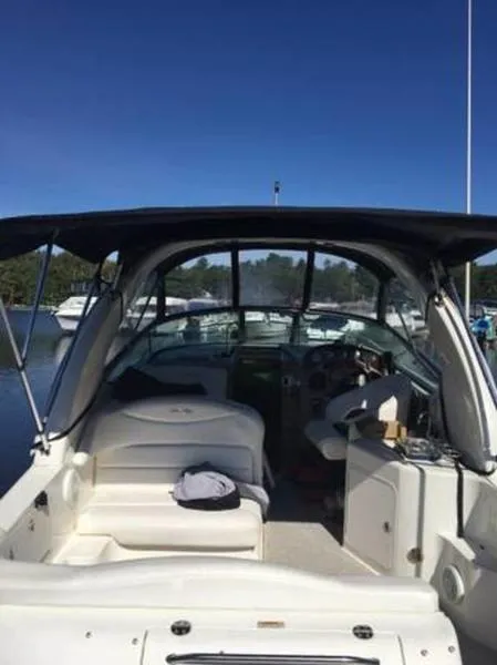 Slide: The Image of 2007 Sea Ray 280 Sundancer boat interior with seating and helm, docked under clear blue sky. - 5