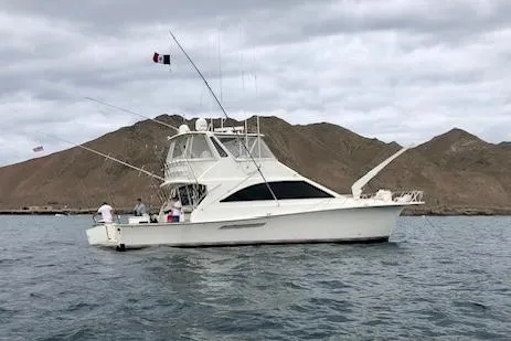 Slide: The Image of 1997 Ocean Yachts 60 Super Sport on water, with fishing rods, near rocky coastline. - 1