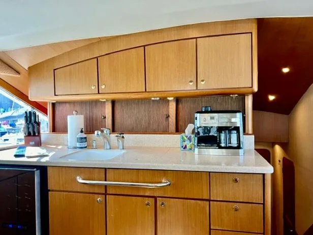 Slide: The Image of 1997 Ocean Yachts 60 Super Sport kitchen with wooden cabinets, sink, and coffee maker. - 11