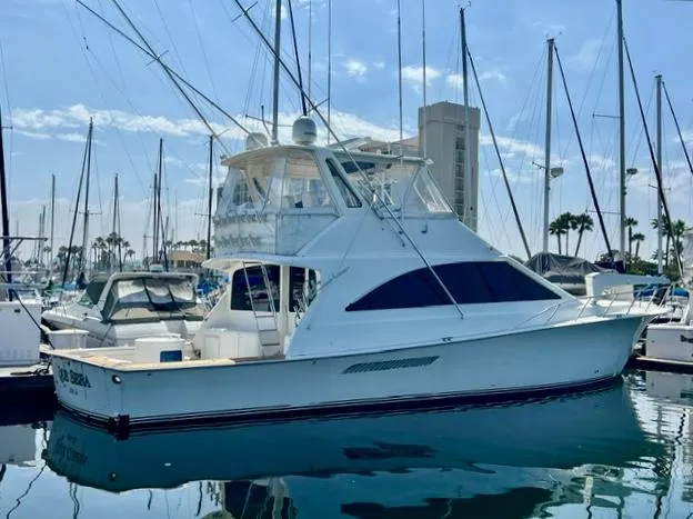 Slide: The Image of 1997 Ocean Yachts 60 Super Sport docked in a marina, surrounded by sailboats. - 2
