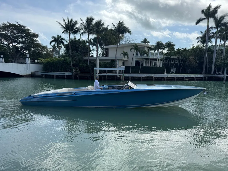 Slide: The Image of 2013 Nor-Tech 420 Monte Carlo boat cruising on a calm waterway, surrounded by palm trees. - 2